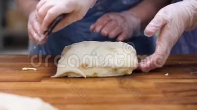 女人在烹饪手套切割膨化糕点与葡萄干成片，食品概念。 库存录像。 双手合拢